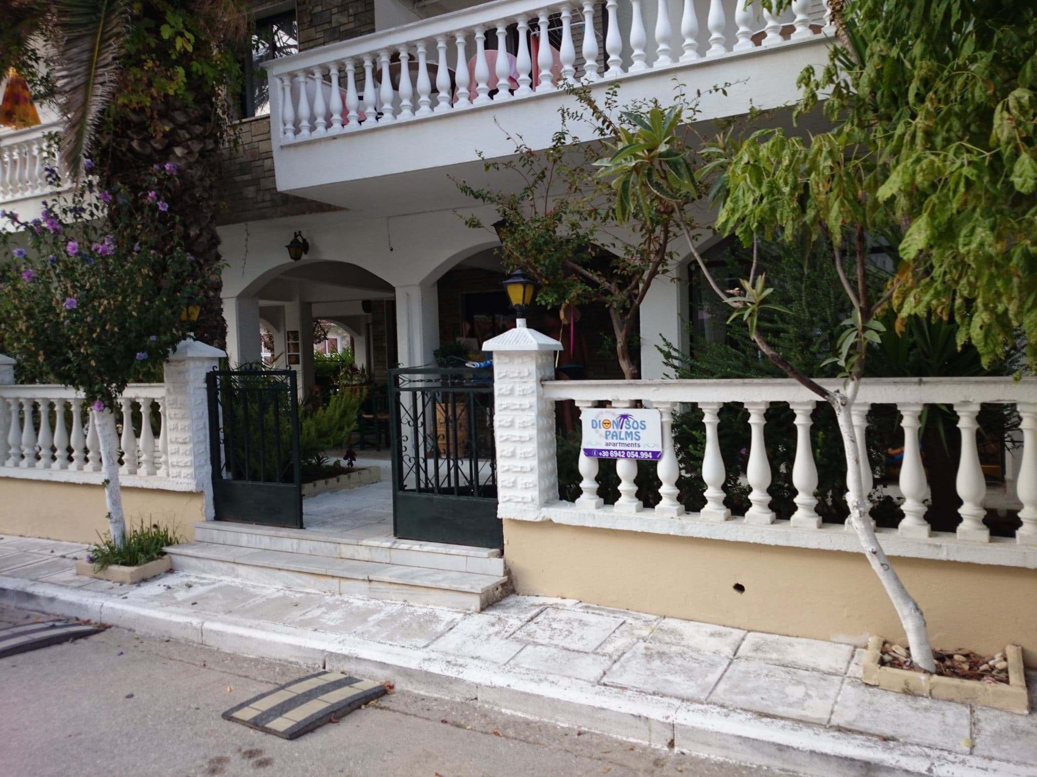 Street view near Dionisos Palms Apartments, Néa Flogitá — © zverik (CC BY-SA · Mapillary)